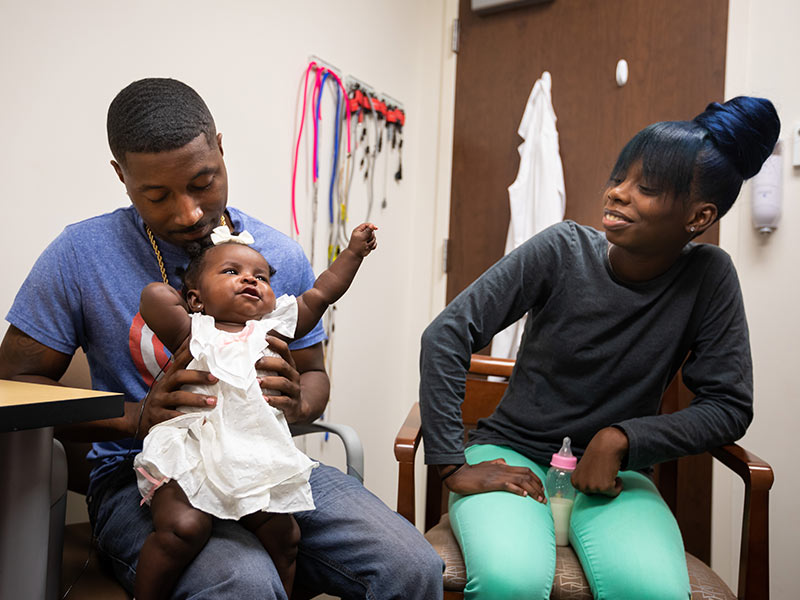 Couple holding baby with cochlear implant.